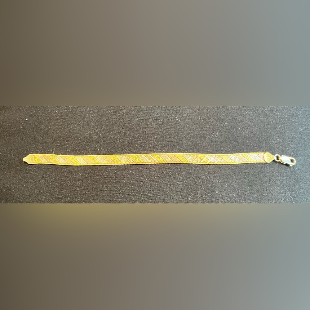 Gold tone bracelet with tri-color design accent.